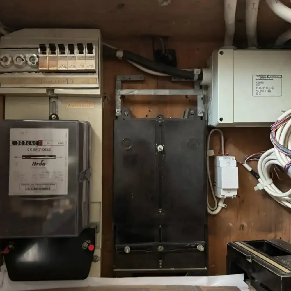 Alte Elektroanlage mit veraltetem Sicherungskasten und Stromzähler